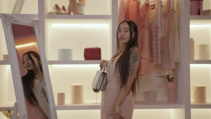 千禧一代亚洲女性选择站在衣柜镜子前的手袋。女性试穿新衣服，微笑着看着相机。