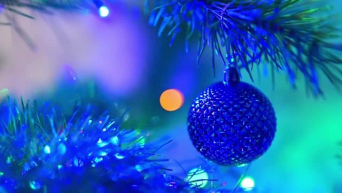 圣诞树上装饰着蓝色玻璃球，在闪烁的灯泡花环背景上的圣诞云杉树枝上。