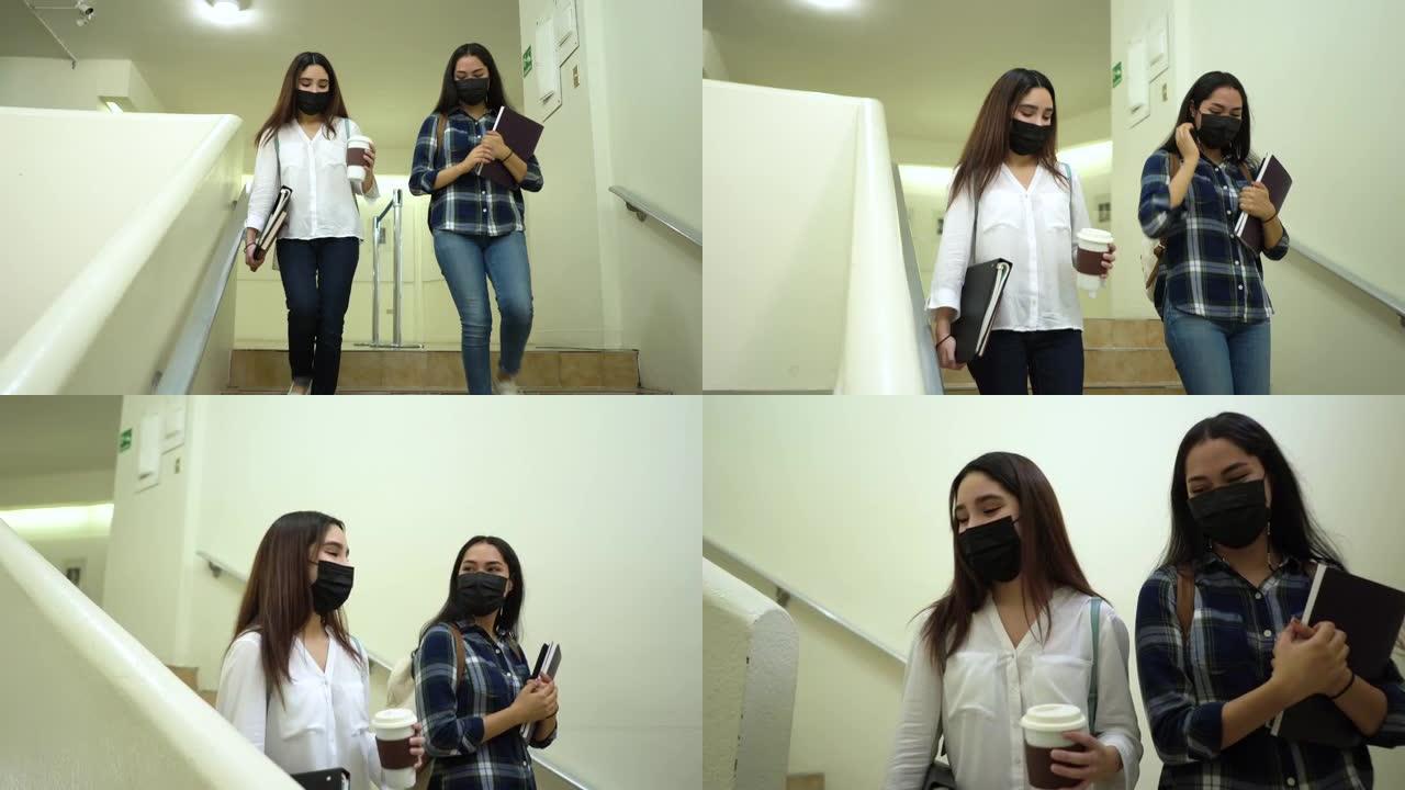 两名戴着口罩的女学生走下楼梯