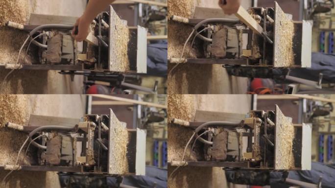 垂直视频。车间的木匠在木工机器上工作，加工和对齐木材以制造家具零件。木板加工后出来，锯末。4k