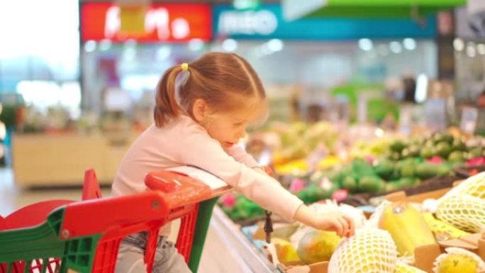 孩子，小女孩5岁坐在超市的购物车，而母亲选择商品购买它的女性孩子购物车食品商店或超市。小孩去购物。