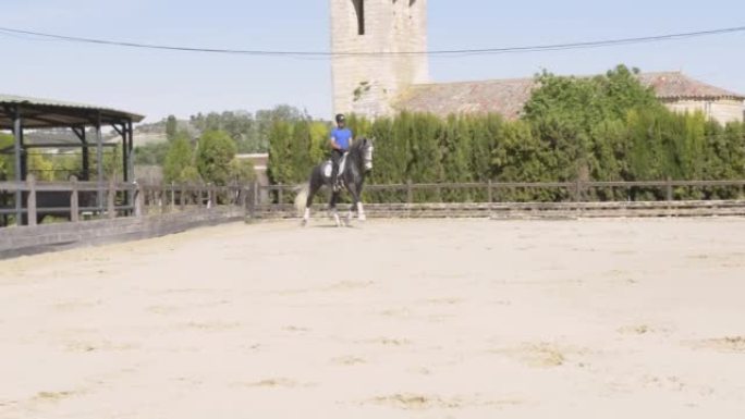 骑师在马术中心训练，骑着一匹白发纯种马。