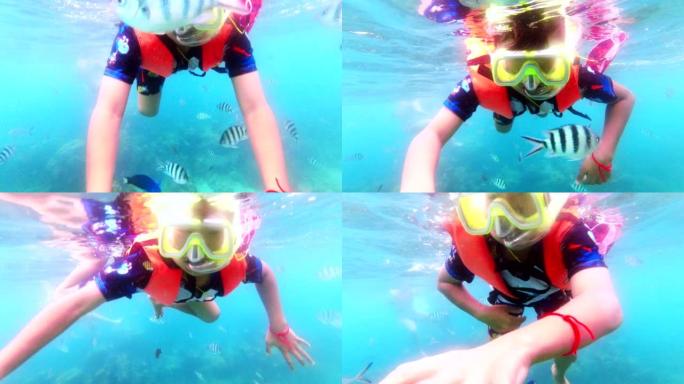 亚洲男孩浮潜，和很多鱼一起游泳。