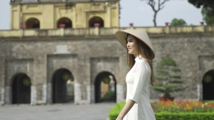 4K越南女子穿着传统服饰，戴着亚洲风格的圆锥形帽子走在唐龙帝国城堡