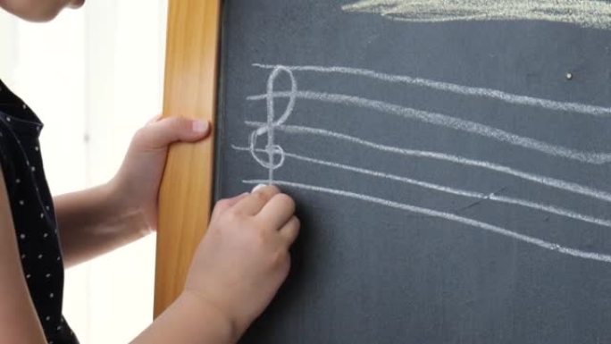女孩，小学适龄儿童写笔记，用粉笔在黑板上写乐谱，黑板上画慢动作，特写。音乐教育、音乐与儿童创意概念
