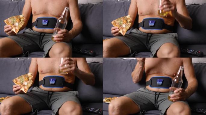 坐在沙发上的男人一边吃披萨，一边喝啤酒，一边使用电子腹部减肥带。不健康的生活方式