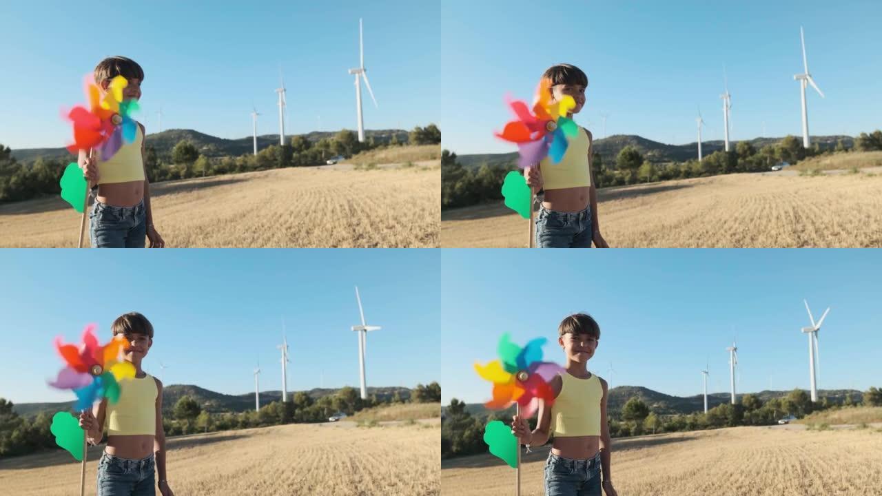 女孩在风场里拿着移动的风力涡轮机玩具看着相机。