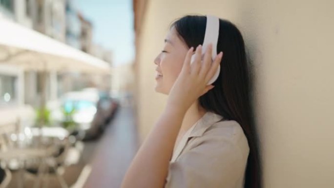 中国女人微笑着自信地在街上听音乐