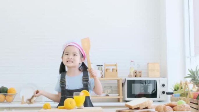 Little girl holding wooden spoons to mix salad and