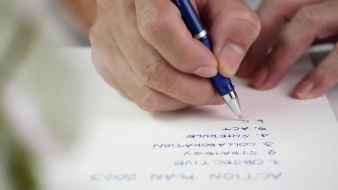 成功的概念，战略，商业计划，目标，目标，管理。商人使用蓝色墨水中性笔书写行动计划清单在木制桌上的笔记