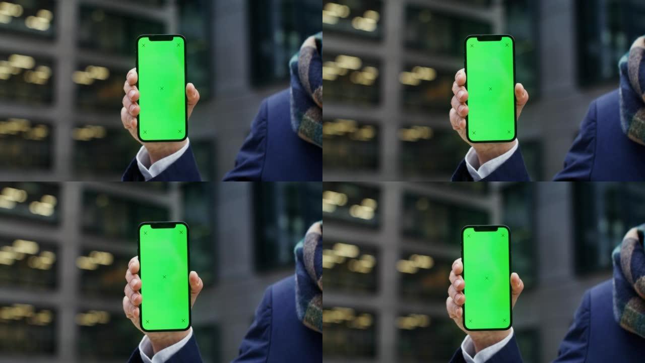 一个穿着暖和的男人拿着绿屏电话
