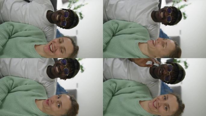 快乐的跨种族夫妇通过手机的前置摄像头进行视频拍摄，挥手致意
