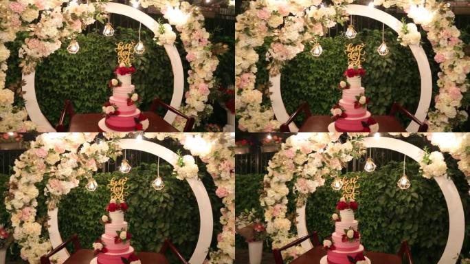 婚礼蛋糕，有史以来最好的一天在绿色花园上签名，为晚上的婚礼派对装饰。白色和玛萨拉创意装饰，圆形婚礼拱