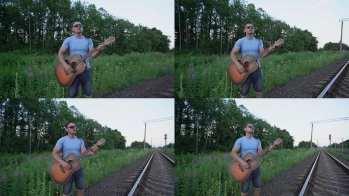 铁路上戴墨镜戴帽男音乐家弹吉他唱歌