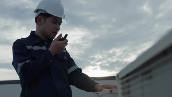 维修工程师根据公司的安装检查压缩机空调。检查员项目使用对讲机呼叫报告在屋顶工厂工作。