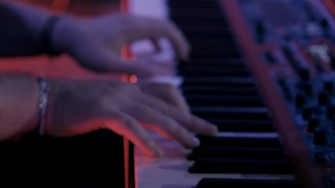 男钢琴家在舞台上弹钢琴。丰富多彩的背景。近距离接触。