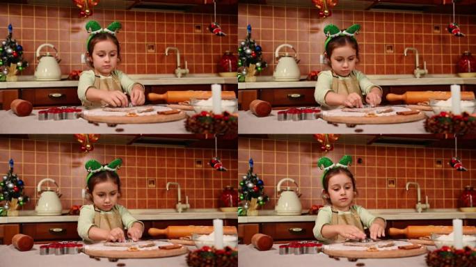 可爱的小女孩头上有精灵箍，围裙站在厨房岛，用姜饼面团切模