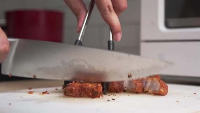 在家用厨房用菜刀在船上手工切割或切碎炸猪肚肉的特写镜头。高胆固醇食物烹饪