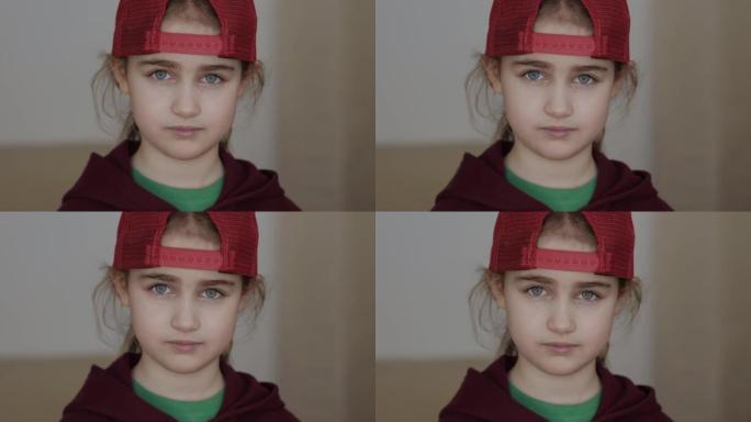 戴着红色棒球帽、金发的年轻严肃女孩在室内看着相机。肖像可爱严肃儿童严肃沉思
担心的高加索少年。悲伤自