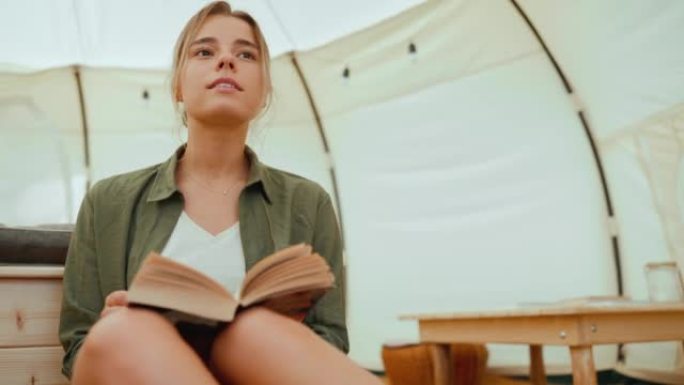 积极的金发女人在帐篷里看书