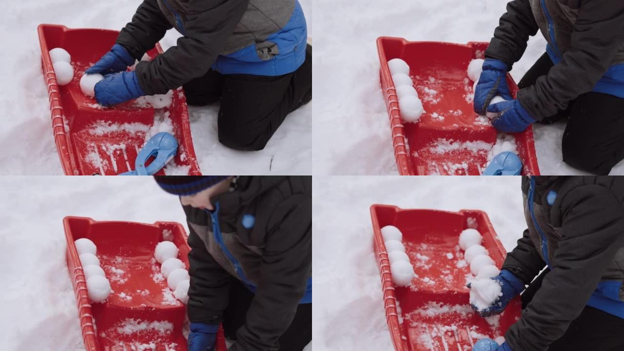 穿着连指手套的孩子用红色雪橇摆出圆形雪球，特写镜头。