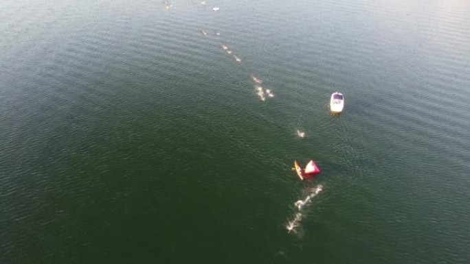 在Penticton钢铁侠2022游泳活动中，人们在海和船只上游泳的无人机拍摄