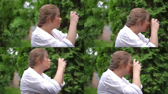 侧视图古玩才华横溢的大码女人在户外绿色花园拍摄夏日自然的照片。快乐自信的高加索摄影师在慢动作微笑中拍
