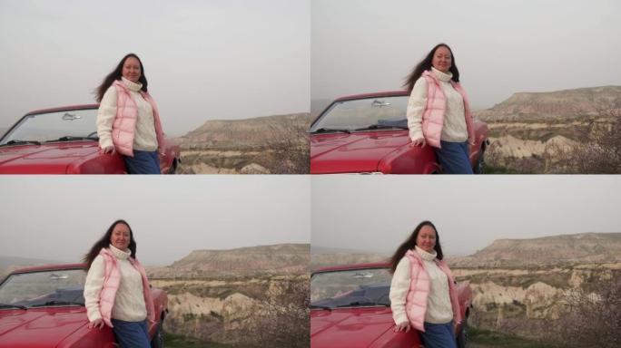 春天，女人站在岩石中复古敞蓬车红色汽车附近。