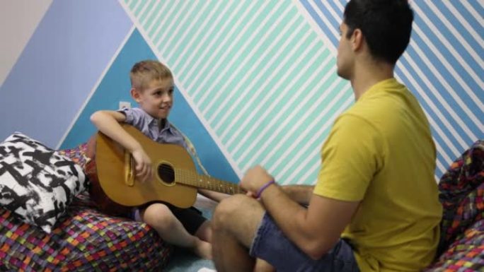 男生在男音乐老师的帮助下学习如何弹奏原声吉他
