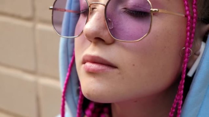 一个悲伤的高加索青少年时髦女孩的肖像，粉红色的辫子在粉红色的砖墙上。Z世代风格