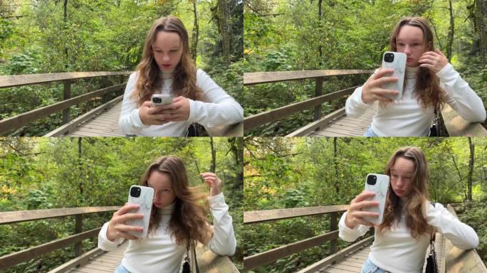 一个穿着白色高领毛衣的女孩拿着手机在她面前自拍，一个白色表壳的女孩少年在大自然的公园里夏天在萨里河上