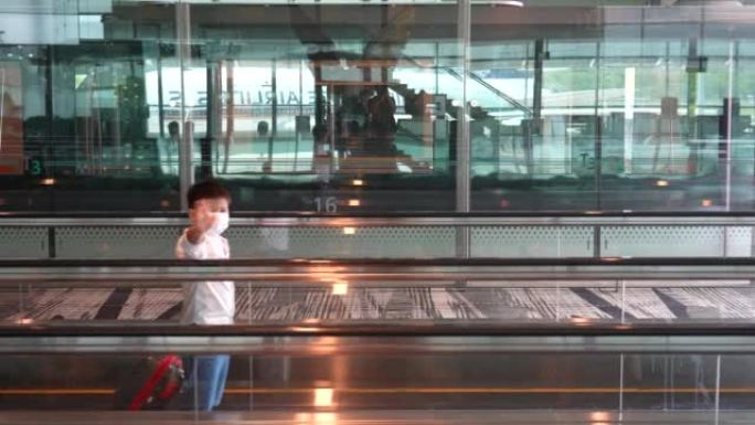 亚洲男孩带着行李在机场候机楼等候
