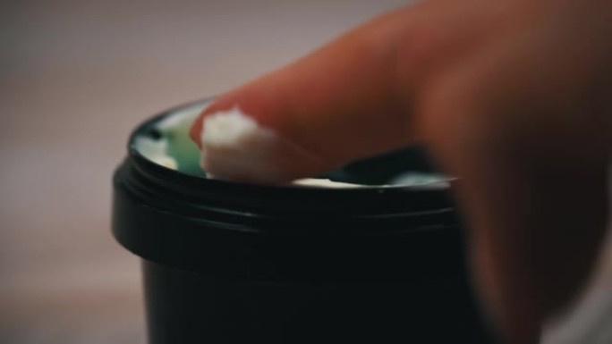 一罐奶油放在桌子上，一个女人的手指把它捡了起来