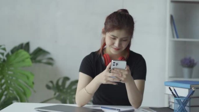 Asian woman wearing headphones talking on smartpho