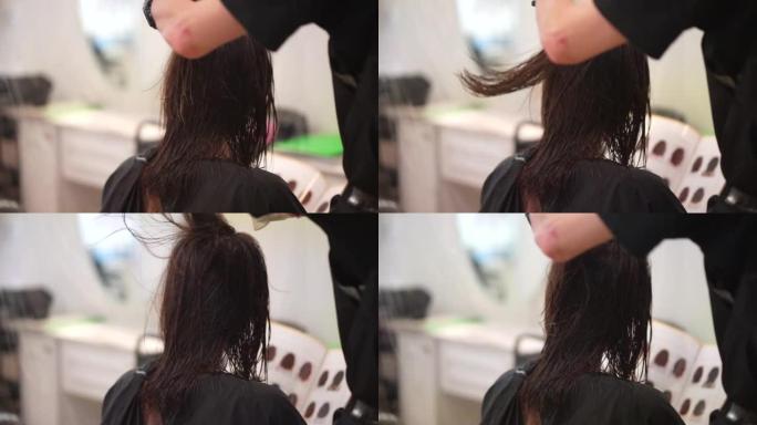 男性理发师用吹风机烘干女性头发