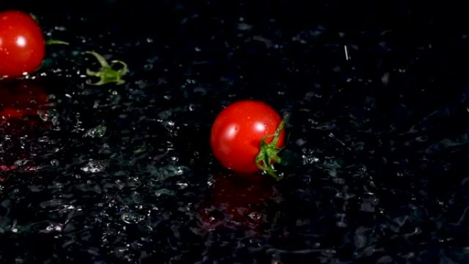 西红柿落入水中，黑色背景上有飞溅和气泡