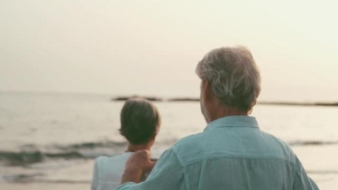 一位老人在海滩上抱着妻子，穿着毛衣一起享受寒冷的假期。相爱的人，一起感到自由