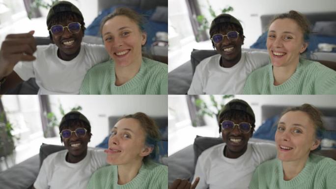 Joyful interracial couple taking selfies with smar