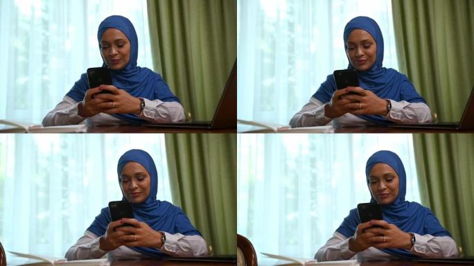 戴头巾的迷人阿拉伯穆斯林妇女，使用手机，滚动新闻提要，浏览网站，检查内容