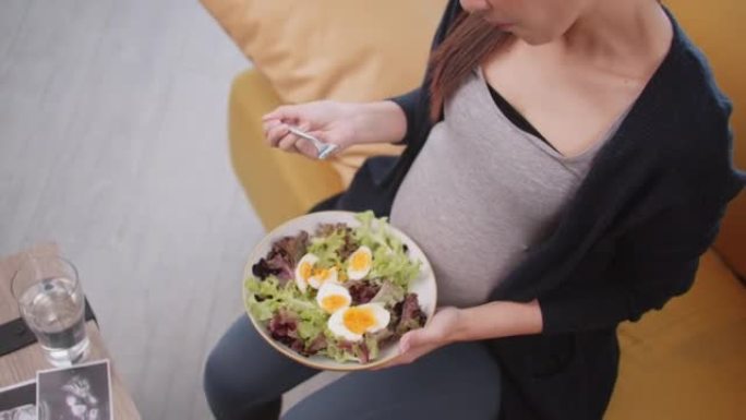 快乐的亚洲孕妇为她未出生的婴儿吃健康食品。