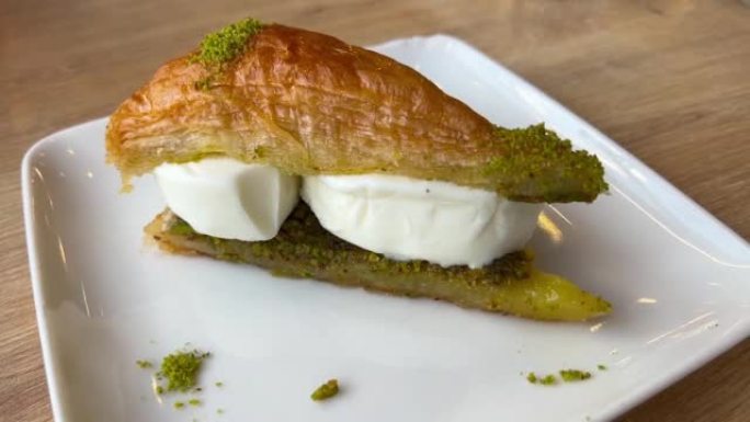 阿拉伯甜果仁蜜饼或baklawa配以餐厅餐桌上的白瓷盘子上的冰激丸