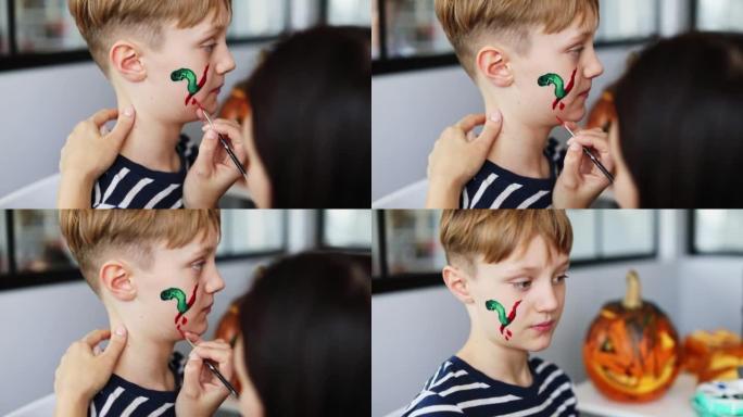 Mother making face painting to her son for Hallowe