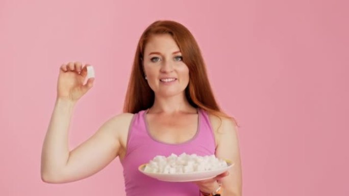 Woman is holding handful of sugar cubes at pink ba