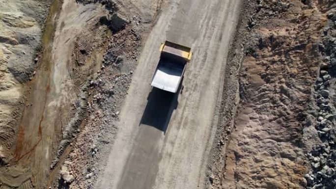 驾驶自卸车运输在金矿开挖采石场挖掘的矿石，空中慢动作拍摄