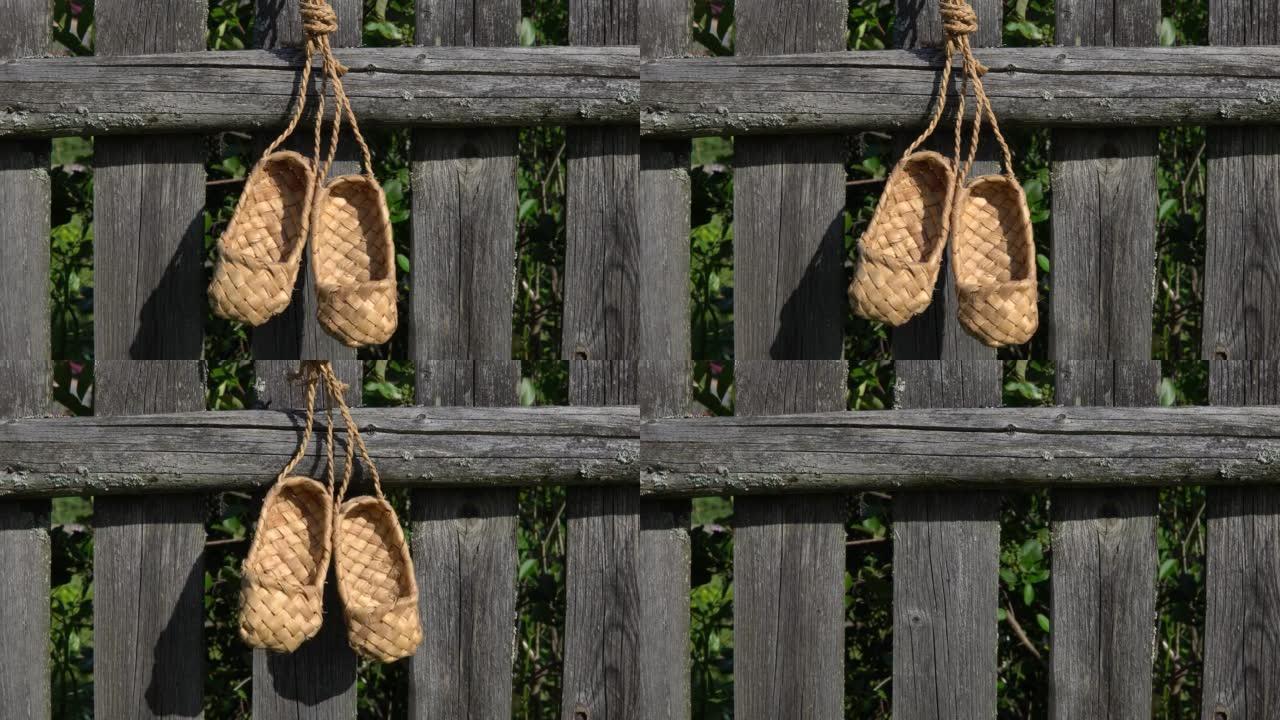 乡村乡村概念。古董手工乡村鞋-韧皮鞋。一双挂在木栅栏上的韧皮鞋。