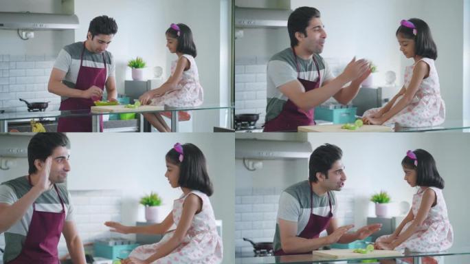 年轻快乐的印度父亲在厨房与女儿互动并准备饭菜