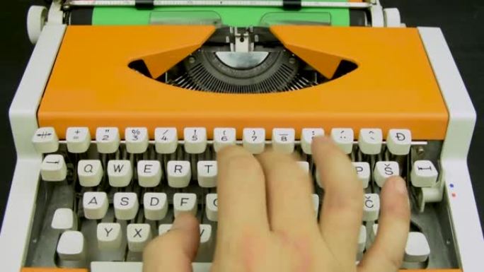在打字机上手工打字时尚橙色复古机械白色键盘绿纸