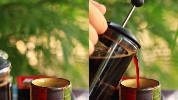 将法国压榨机中的咖啡倒入彩色陶瓷杯中