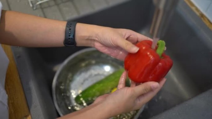 一位亚洲妇女的手在厨房里洗红色甜椒。怀孕期间健康的生活方式。