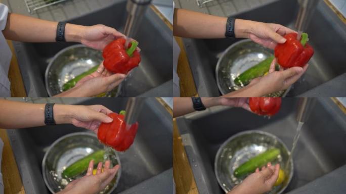 一位亚洲妇女的手在厨房里洗红色甜椒。怀孕期间健康的生活方式。